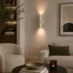 5lamp Capsule Krem duvar apliği, modern oturma alanında sıcak ışık etkisiyle kullanılıyor