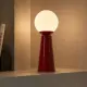 5lamp Lumia Kırmızı masa lambası, duvar rafında yumuşak opal cam ışığıyla kullanılıyor